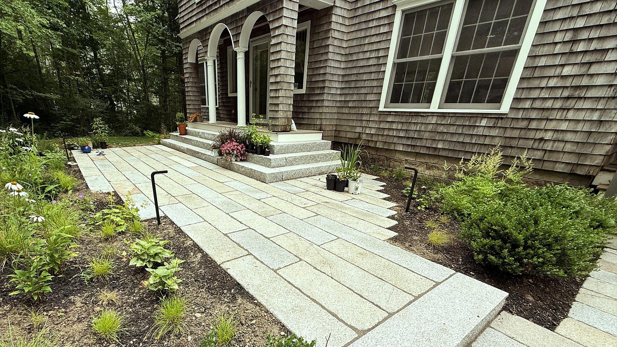 Granite walkway and steps to a shingled house entry